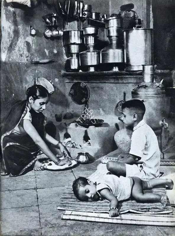 Bacha, Major R. A. (Photographer). A Mill Labourer's Wife Prepares a Meal with Her Children by Her Side, n.d. | Contemporary Photograph