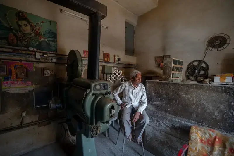Hemant Chaturvedi (Photographer), The projectionist of Chandrakant Talkies, Jasdan, Gujarat standing alongside the projection apparatus, 2024, Contemporary Photograph