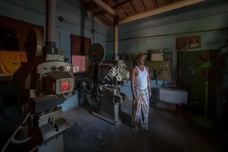 Hemant Chaturvedi (Photographer), The projectionist of Jagadambika Talkies, Elapully, Kerala standing alongside the projection apparatus, 2024, Contemporary Photograph