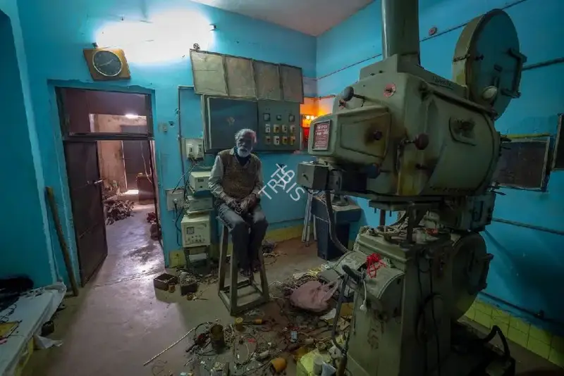 Hemant Chaturvedi (Photographer), The projectionist of Aakriti Talkies, Rewa, Madhya Pradesh standing alongside the projection apparatus, 2024, Contemporary Photograph