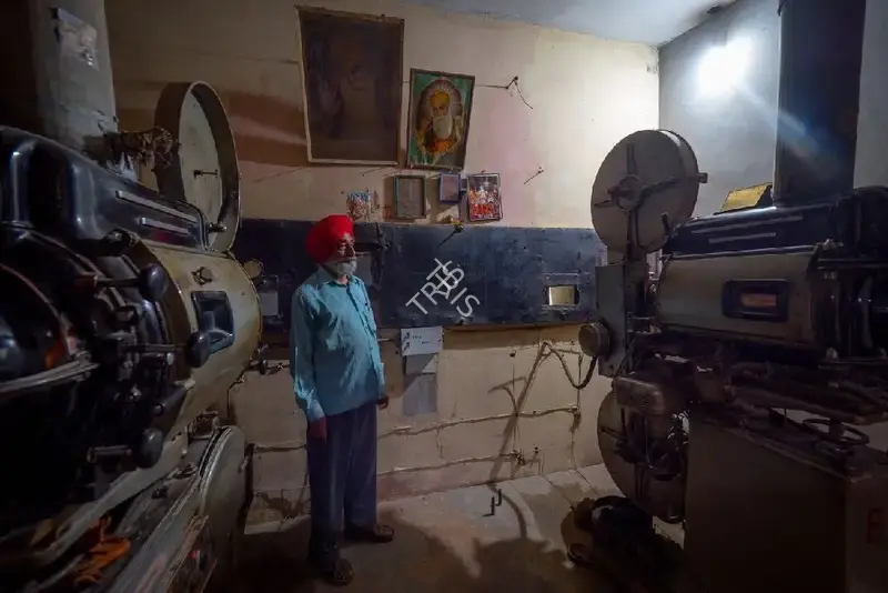 Hemant Chaturvedi (Photographer), The projectionist of Karnail Talkies, Muktsar, Punjab standing alongside the projection apparatus, 2024, Contemporary Photograph