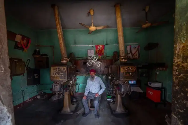 Hemant Chaturvedi (Photographer), The projectionist of Krishna Talkies, Amritsar, Punjab standing alongside the projection apparatus, 2024, Contemporary Photograph