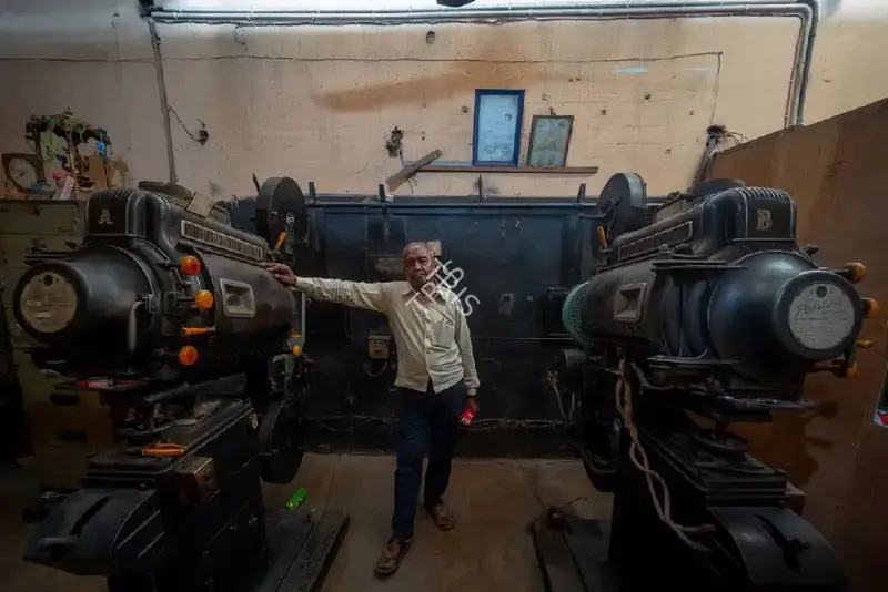 Hemant Chaturvedi (Photographer), The projectionist of Jagat Talkies, Meerut, Uttar Pradesh standing alongside the projection apparatus, 2024, Contemporary Photograph