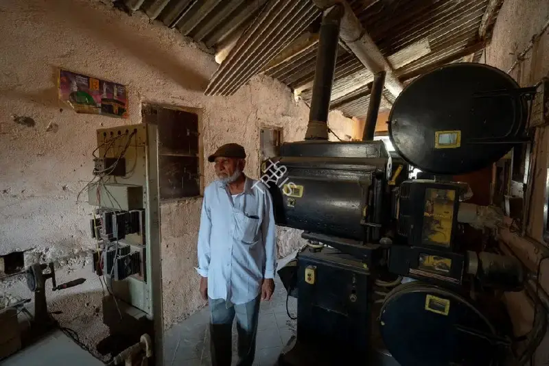 Hemant Chaturvedi (Photographer), The projectionist of Capitol Talkies, Jetpur, Gujarat standing alongside the projection apparatus, 2024, Contemporary Photograph