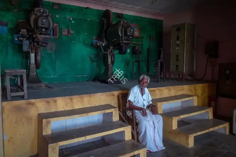 Hemant Chaturvedi (Photographer), The projectionist of Karthikeyan Talkies, Arani, Tamil Nadu standing alongside the projection apparatus, 2024, Contemporary Photograph